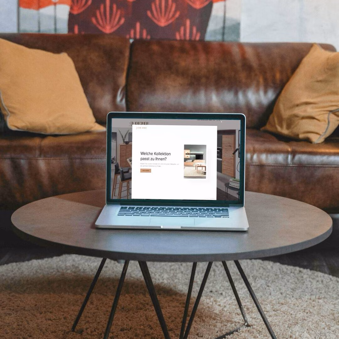 A laptop on a living room coffee table shows a pop-up asking which furniture collection suits the visitor.