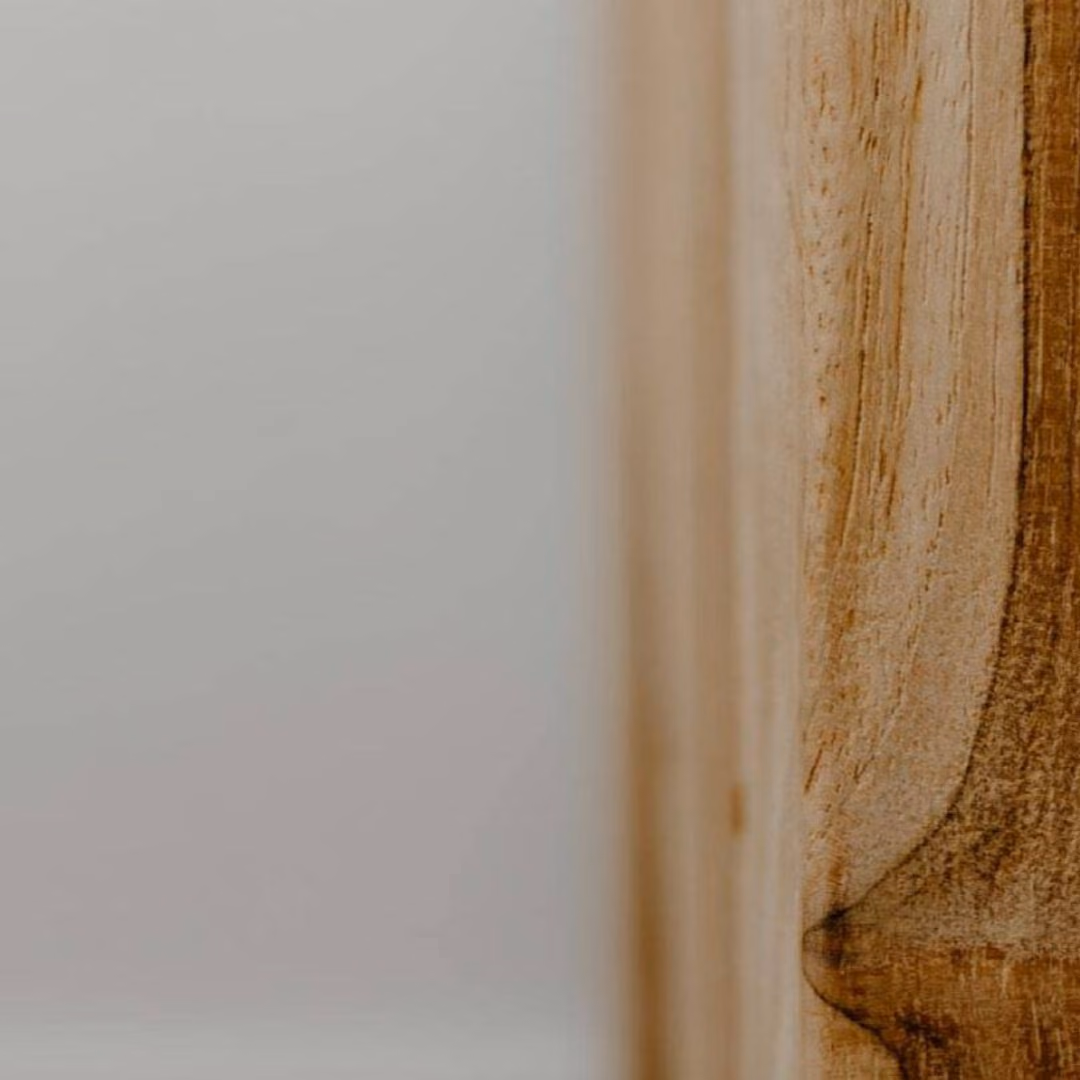 A blurred close-up of a solid wood post against a pale wall.