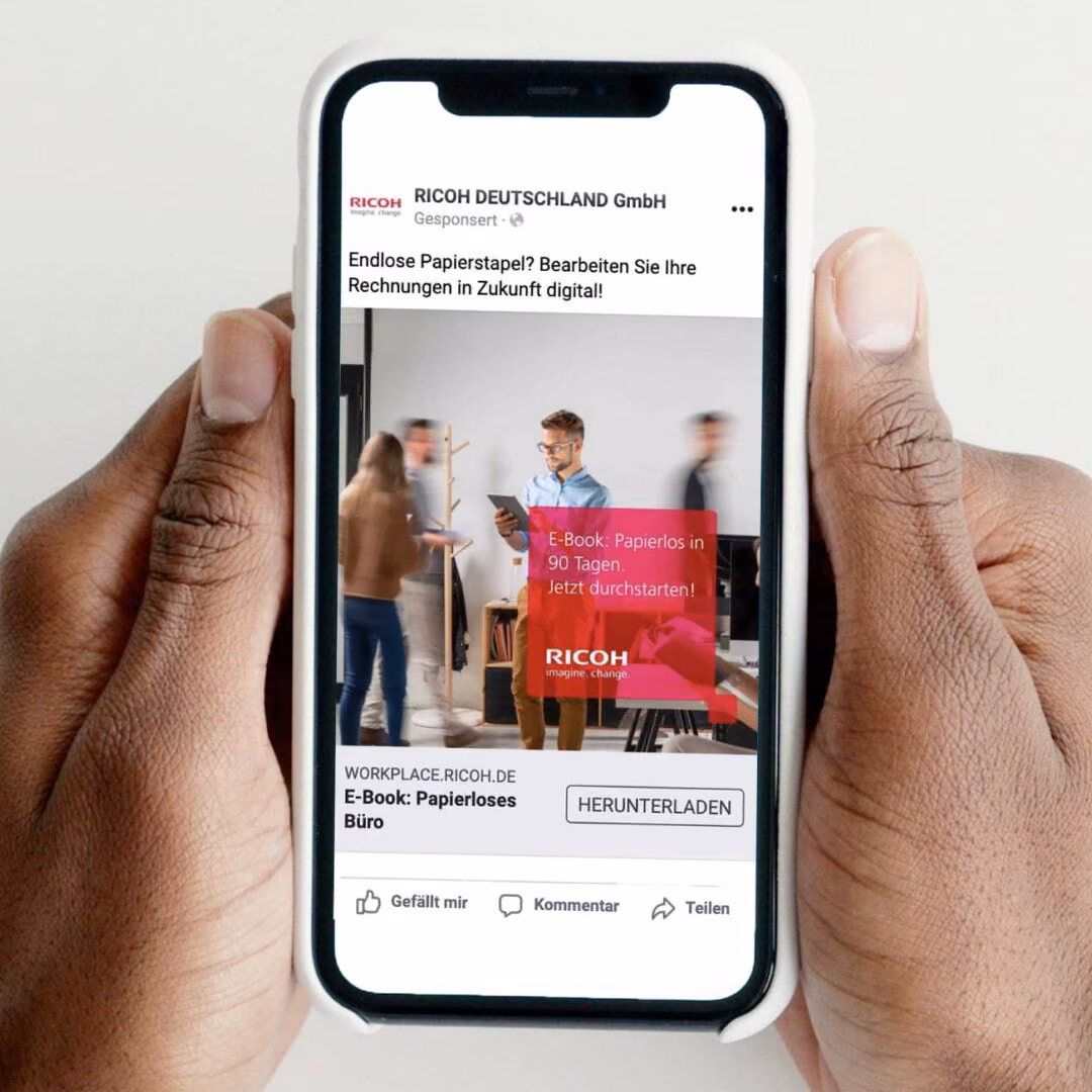 A Ricoh campaign ad on a phone held in both hands.