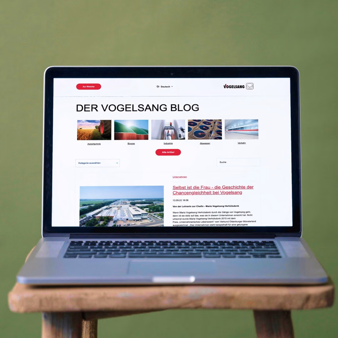 A laptop on a wooden stool shows "Der Vogelsang Blog" with category tiles for agricultural technology, biogas, industry, waste water and transport above the newest article.