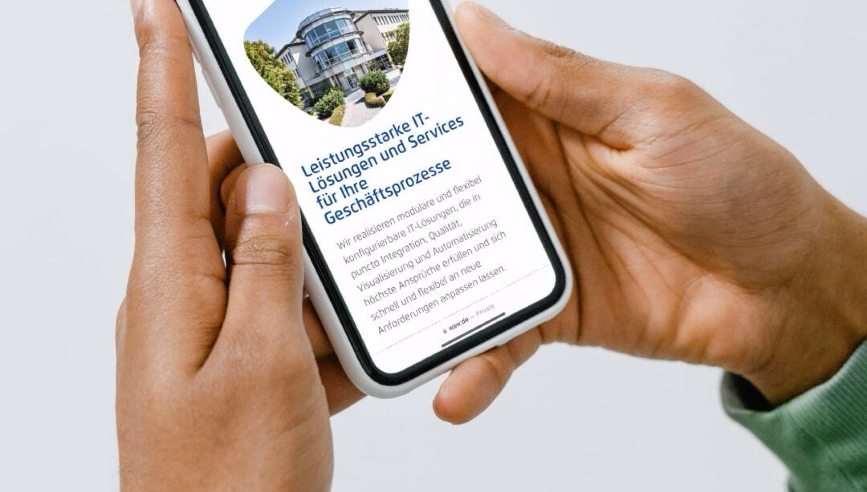 Hands hold a phone showing the WSW Software mobile site with a photograph of the company building.