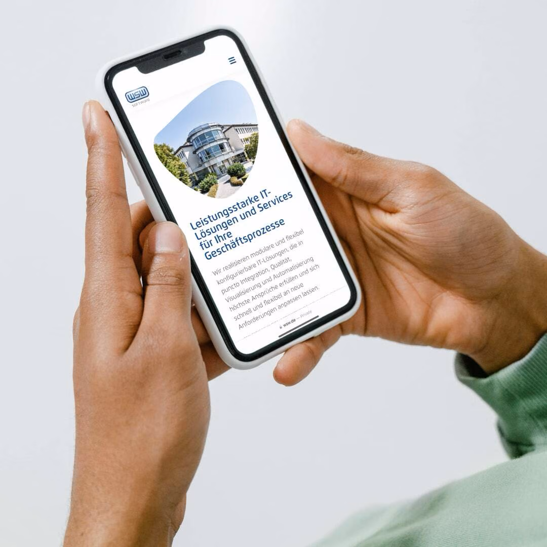 Hands hold a phone showing the WSW Software mobile site with a photograph of the company building.