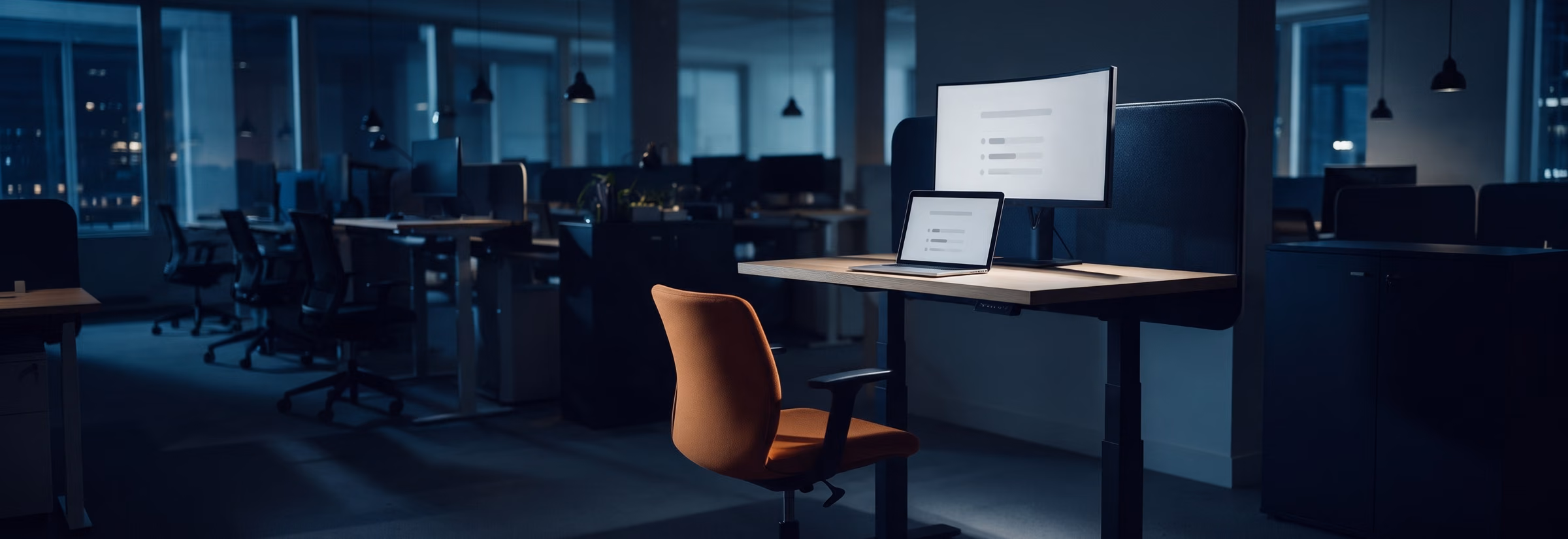 A tidy sit-stand desk at night, a curved monitor and a laptop showing several tasks progressing on their own.