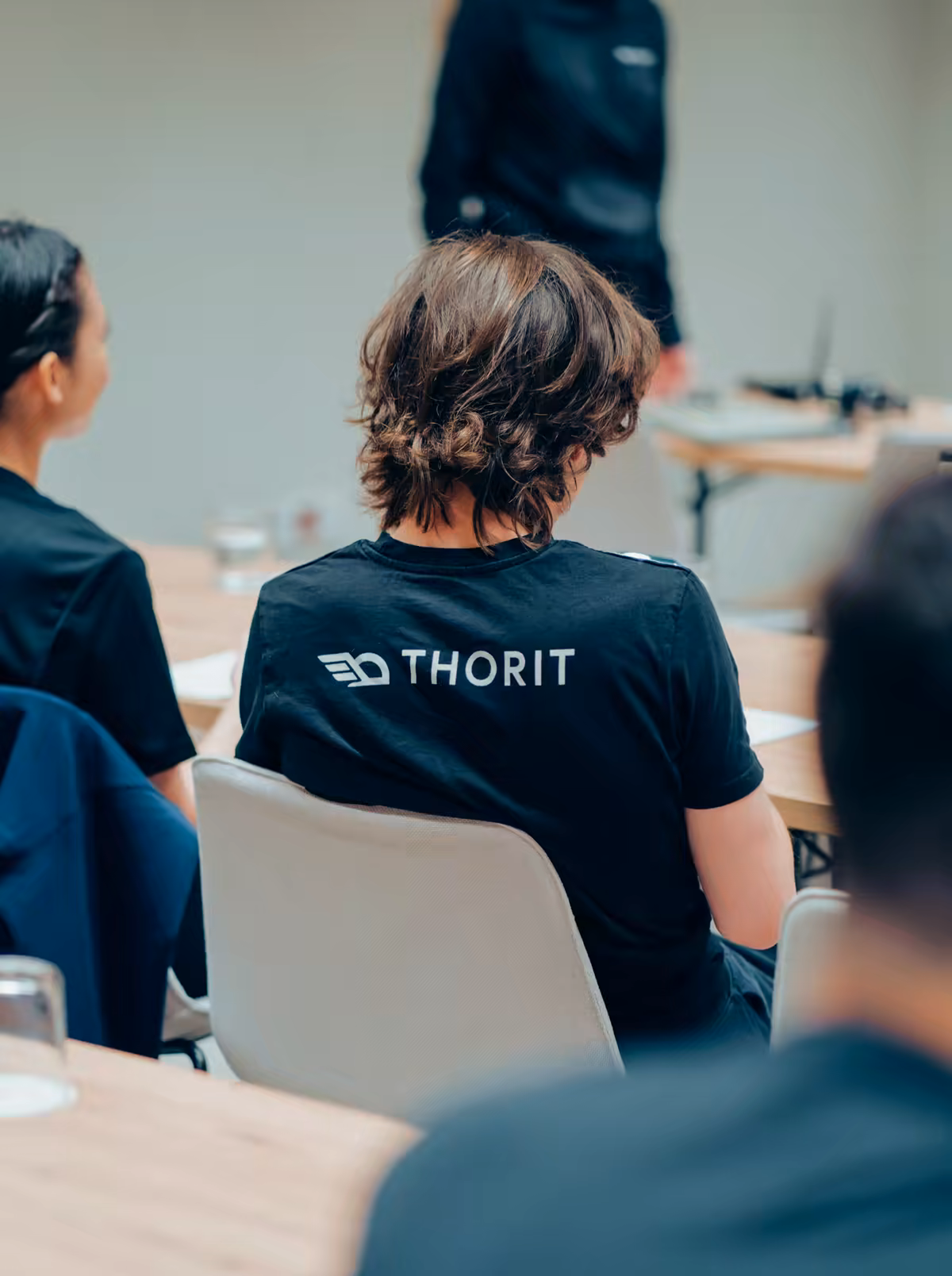 Team members in Thorit shirts following a session at a long table in the office.